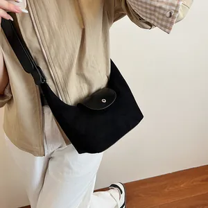 Detail of a black suede crescent shoulder bag with leather flap and silver metal buckle