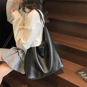 Close-up of black lychee texture leather tote bag worn by a model in casual style