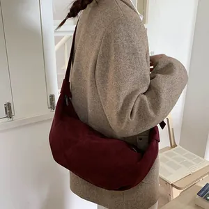 Detailed texture of burgundy suede crescent bag with a matte finish and shoulder strap