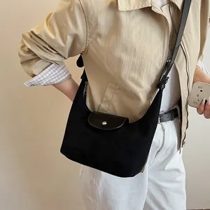 Detail of black suede crescent bag with silver snap closure worn by model