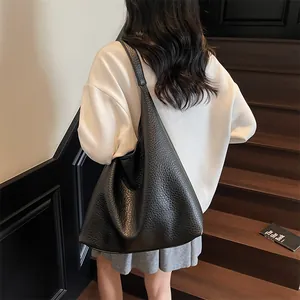 Detailed view of black pebbled leather tote bag with wide shoulder strap on model