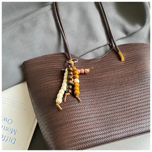 Close-up of dark brown woven tote bag featuring a decorative wooden bead charm