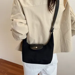 Side view of black suede shoulder bag with leather flap and silver snap button on model