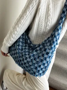 Vintage denim checkered crossbody bag with fringe edges on a white sweater background