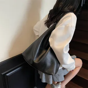 Detail of black pebbled leather tote bag showing spacious design on a model