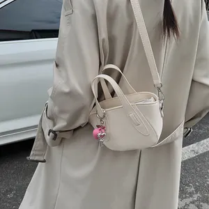 Dettaglio borsa a tracolla in pelle beige con ciondolo a cuore rosa e chiave argentata