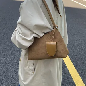 Close-up of brown suede hobo bag with mini leather pouch detail on a trench coat