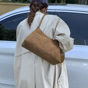 Brown suede shoulder bag styled with a beige trench coat for a minimalist vintage look