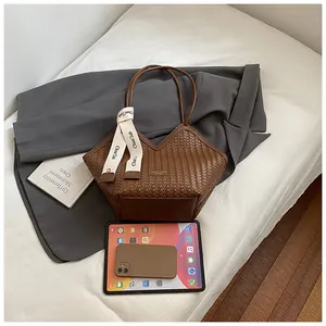 Vue détaillée du sac cabas marron à texture tressée avec ruban décoratif élégant