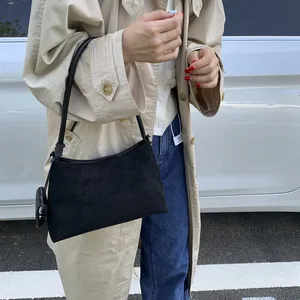 Chic black suede baguette bag styled with a beige trench coat for a trendy street look