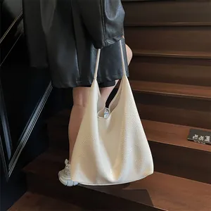 Detailed texture of off-white lychee pattern leather tote bag carried on wooden stairs