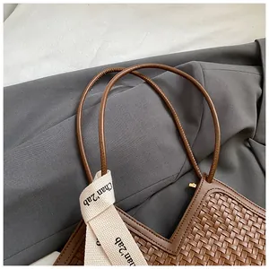 Détail du sac cabas tressé marron avec bandoulière contrastée et broderie chic