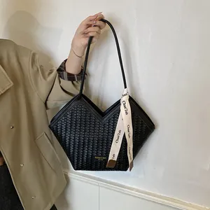 Gros plan d'un cabas noir à texture tressée avec un foulard en soie décoratif imprimé