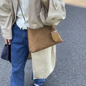 Close-up of brown suede shoulder bag with side round pouch in outdoor street setting