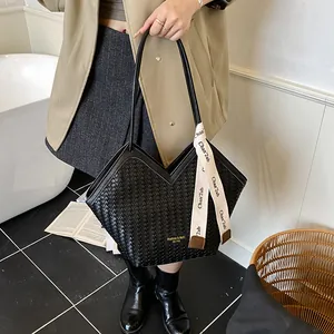 Détail du sac cabas tressé noir avec ouverture en V et foulard décoratif imprimé