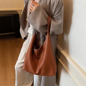 Close-up of brown litchi pattern leather tote bag shown on model in minimalist setting