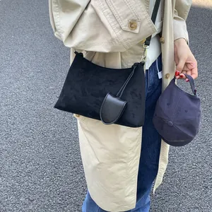 Street style shot of black suede shoulder bag with small pouch and silver hardware