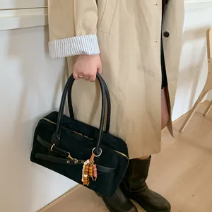 Detail of black suede shoulder bag with long handle and stylish wooden bead charm