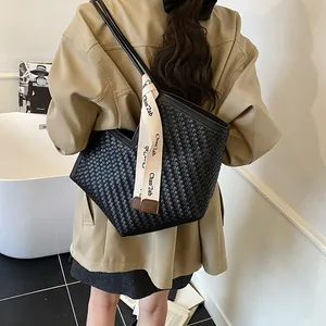 Vue détaillée du sac cabas tissé noir avec ouverture en V et bandoulière lettrée