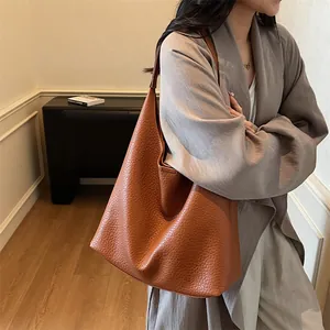 Detailed close-up of brown pebbled leather hobo tote bag on shoulder for commute