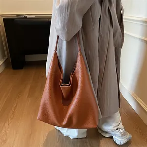 Brown leather hobo tote bag with lychee texture shown on model for daily commuting style