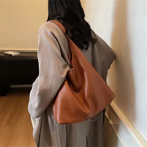 Close-up of caramel leather tote bag with lychee texture on woman shoulder for daily work
