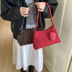 Detail of suede shoulder bags in brown and red with knot strap and mini pouch charm