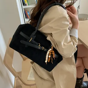 Detail of vintage matte black shoulder bag with wood bead tassel and golden hardware