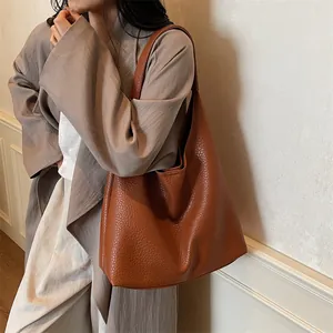 Detail of a large brown tote bag showing the high-quality lychee grain leather texture