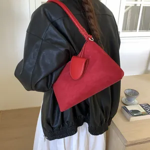 Detail of red suede underarm bag with mini pouch and pleated strap on a leather jacket