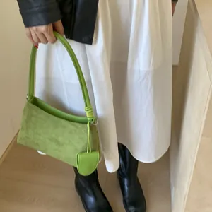 Close-up of green suede shoulder bag with spiral handle and mini charm details