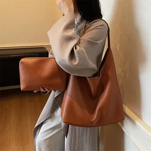 Detail of brown litchi pattern leather tote bag and matching clutch set for women