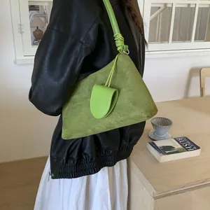 Detail showing the grass green faux suede shoulder bag with decorative mini pouch