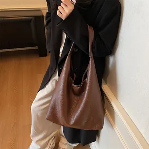 Detail of dark brown tote bag showing lychee grain texture and soft hobo structure