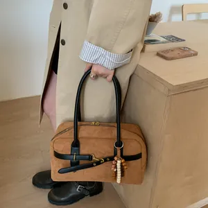 Detail of dark camel suede Boston bag with leather straps and ethnic wood bead charm