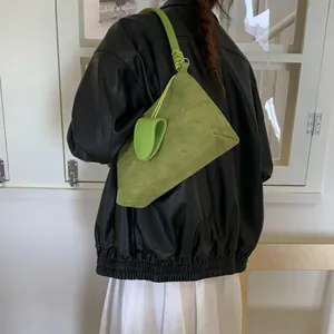 Close-up of grass green suede Hobo bag with knot shoulder strap detail on model