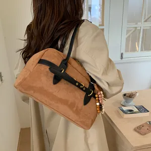 Detail of brown suede handbag with decorative bohemian beads and gold hardware