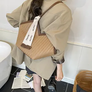 Détail d'un sac cabas tissé avec bordure contrastée et ruban décoratif à lettres chic