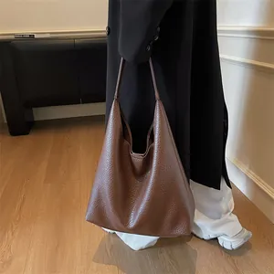 Detail of a large brown pebbled leather tote bag shown on a model for daily commute