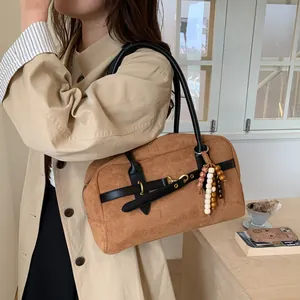 Detail of a brown vintage Boston bag with colorful bead tassel and gold hardware