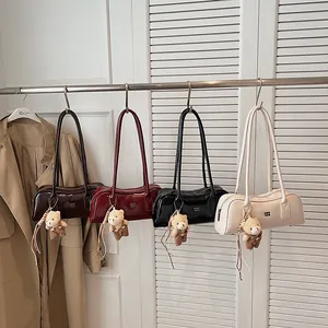 Reihe glänzender Boston-Taschen in vier Farben mit süßen Bären-Anhängern am Ständer
