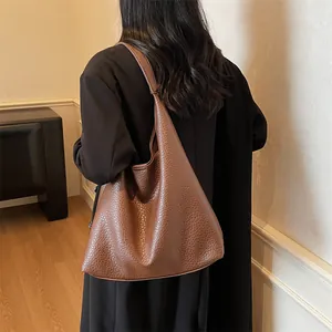 Detail of a dark brown pebble texture faux leather hobo shoulder bag with wide strap