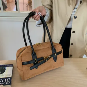Detail of a brown suede Boston handbag featuring black leather straps and gold hardware