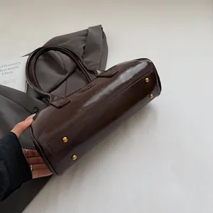 Detailansicht der braunen Boston Bag mit Goldnieten und polierter Öl-Wachs-Lederstruktur