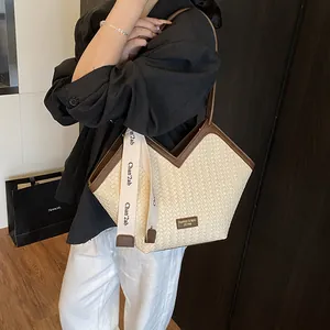 Vue détaillée du sac cabas tressé crème avec bordure marron et ruban décoratif