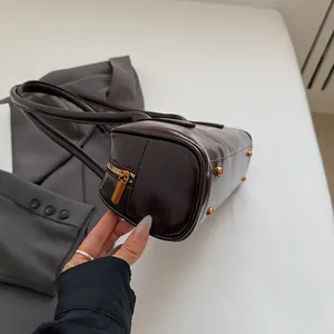 Detailansicht einer dunkelbraunen Lackleder-Schultertasche mit goldenen Beschlägen