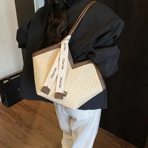 Vue détaillée du sac cabas tissé avec bordure en cuir contrasté et sangles logo