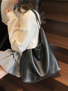 Minimalist large black pebbled leather tote bag for women shown on shoulder in daily use