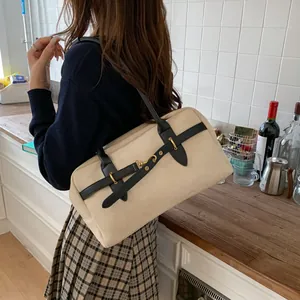 Detail of a retro beige rectangular shoulder bag with black leather straps and gold buckle