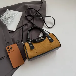 Detail of vintage brown suede Boston bag with metal pin accents in a lifestyle setting